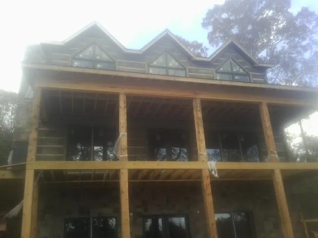 Dormers and porch framing on a large log home under construction — Roof Coating work by our crew in Nichols